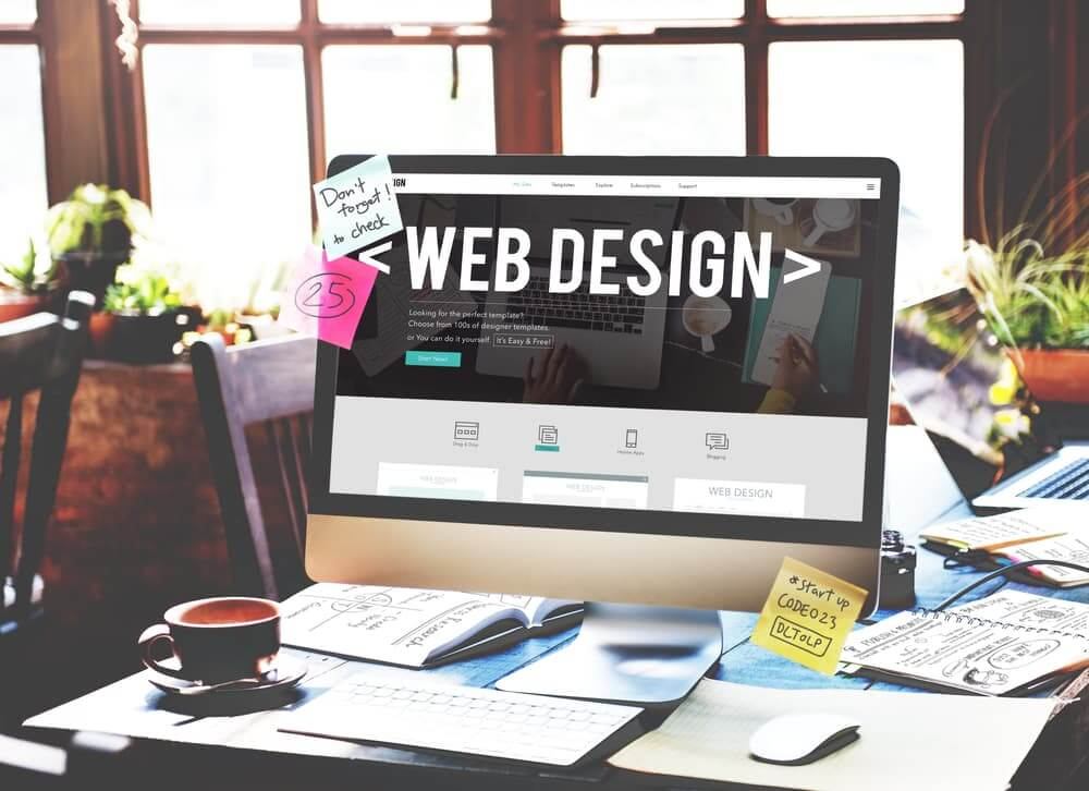 Web design workspace with computer monitor displaying a website layout and design tools